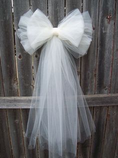 a white tulle bow hanging on a fence