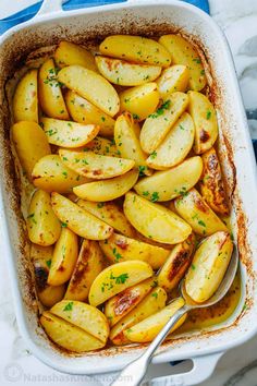 baked potatoes with parsley in a white casserole dish, ready to be eaten