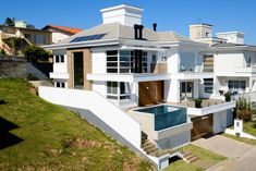 an aerial view of a modern house with pool in the foreground and other houses on the hillside behind it