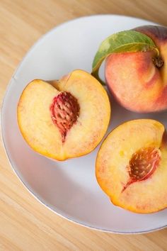 two peaches on a plate with one cut in half