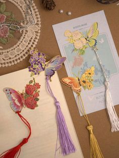 paper butterflies and tassels sitting on top of a table next to an open book