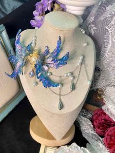 Dive into a world of enchantment with our Ethereal Mermaid Fairy Wing Choker. This stunning piece embodies the magic where sea meets sky, blending the allure of mermaids with the whimsy of fairies. Key Features: * Handcrafted iridescent wings that shimmer with every movement * Mesmerizing blue and purple hues reminiscent of twilight over calm seas * Unique asymmetrical design featuring a delicate gold-toned centerpiece * Choker style for a close, elegant fit Artisan Craftsmanship: Each wing is a Handmade Iridescent Magical Jewelry, Mystical Iridescent Necklaces As Gifts, Water Fairy Jewelry, Handmade Iridescent Fantasy Jewelry, Ethereal Mermaid, Iridescent Mystical Pendant Jewelry, Ethereal Fairy, Iridescent Wings, Magical Accessories