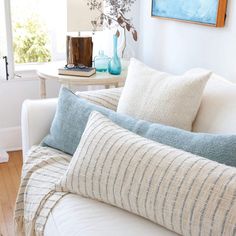 a living room filled with white furniture and blue vases on top of a table