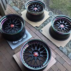 four black rims with colorful lights on them sitting on top of a brick walkway