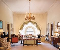 a living room filled with lots of furniture and a chandelier hanging from the ceiling