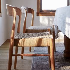 three wooden chairs sitting next to each other on top of a rug in front of a window