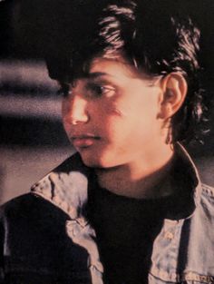 a young man wearing a denim jacket and earring