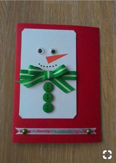 a christmas card with a snowman made out of buttons and green ribbon on it