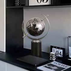 a black and white photo of a desk with a silver globe on top of it