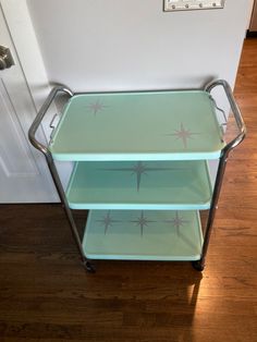 three tiered serving cart with star designs on the side and bottom shelf, sitting in front of a door