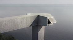 a concrete structure overlooking the ocean on a foggy day with an opening in it