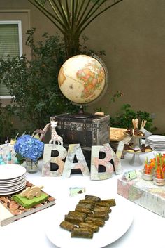 a table topped with plates and bowls filled with desserts next to a baby sign