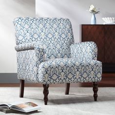 a blue and white patterned chair sitting on top of a rug next to a book