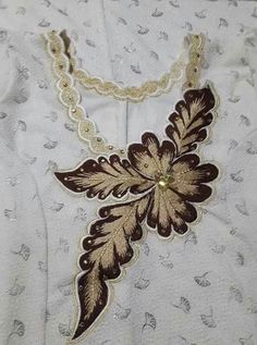 a white shirt with brown and gold designs on the front, attached to a chain