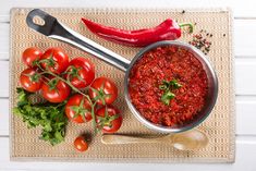 tomatoes and other vegetables on a mat next to a spoon