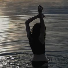 a woman standing in the water with her arms up