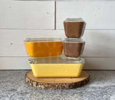 there are three containers with different foods in them on a wooden stand next to a white wall