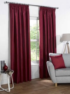 a living room filled with furniture and a window covered in red drapes next to a chair