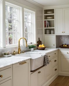 a kitchen with white cabinets and gold faucets on the windowsills is shown