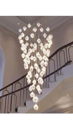 a chandelier hanging from the ceiling in a room with stairs and railings