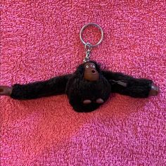 a monkey keychain laying on top of a pink towel with a black face