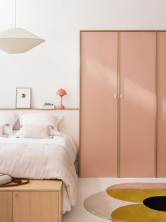 a bedroom with pink cabinets and white bedding