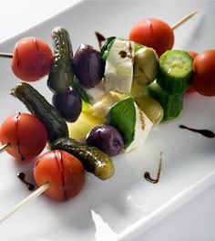 a white plate topped with lots of veggies on skewered in sauce