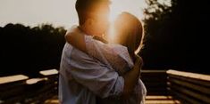 a man and woman embracing each other in front of the sun