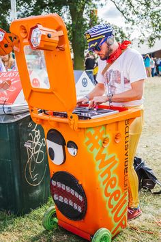 a man in an orange ice cream machine at a festival with other people around him