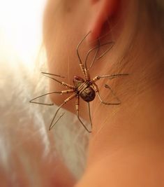 a close up of a person's ear with a spider attached to the back of it