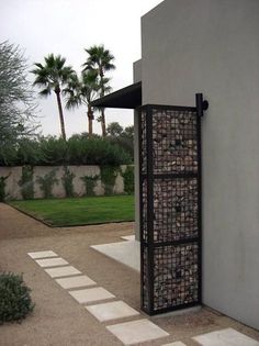 an open door on the side of a building with grass and palm trees in the background