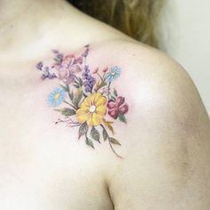 a close up of a woman's chest with flowers tattooed on her left shoulder