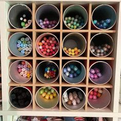 several buckets filled with different colored crayons on top of a wooden shelf