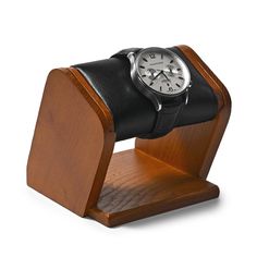 a wooden stand with a watch on it and a black leather strap around the wrist