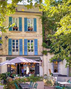 an outdoor cafe with tables and chairs in front of blue shutters on the windows