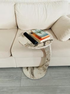 a marble table with books on it in front of a white couch