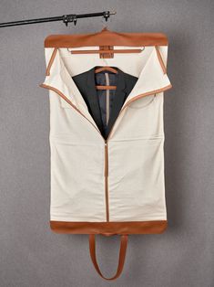 a jacket hanging on a clothes hanger with a cross in the middle and brown leather straps