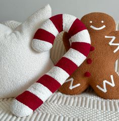 two stuffed gingerbreads sitting next to each other on a white blanket with red and white stripes