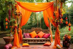 an outdoor seating area with orange drapes and pillows