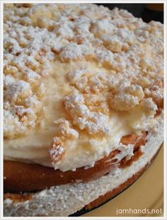 a cake with white frosting and powdered sugar on top sitting on a plate