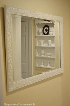 a mirror that is hanging on the wall above a shelf with vases in it