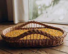 a wicker basket sitting on top of a wooden floor next to a glass window