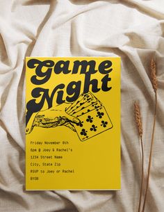 a yellow game night book laying on top of a white sheet with some brown grass