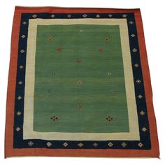 a green rug with blue and red trimmings on the bottom, in front of a white background