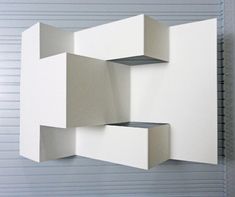 an artistic sculpture made out of white cubes on a gray wall in front of a garage door