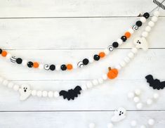 a white wooden background with black and orange halloween decorations hanging from it's sides