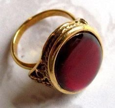 a gold ring with a red stone in the center on a white tablecloth background