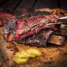 some meat is on a cutting board with pickles