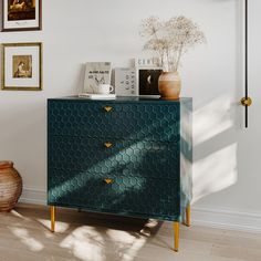 a blue chest of drawers in a room with pictures on the wall and vases