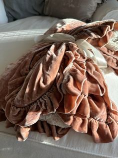 a pile of blankets on top of a bed with white sheets and pillows in the background